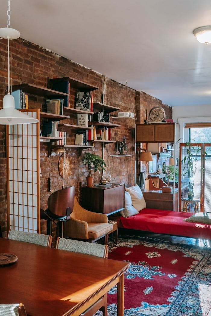 Interior of stylish loft room with classic wooden furniture near brick wall and ornamental rug in sunlight